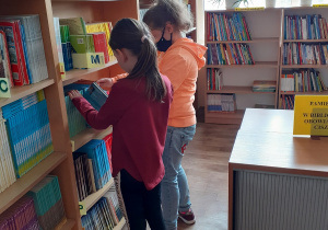 Dzieci z klasy 1 a wybierają książki do wypożyczenia.
